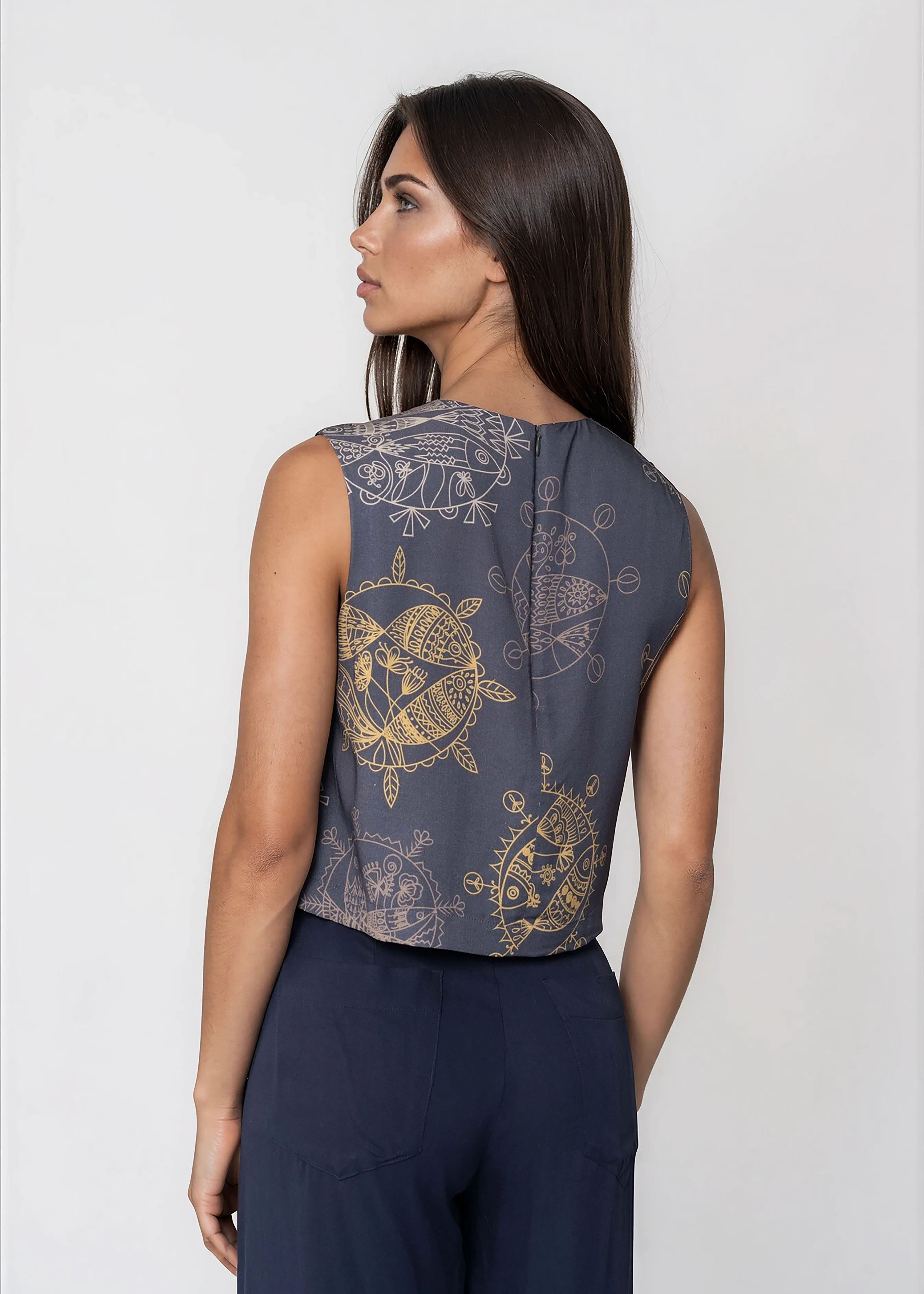 Woman wearing a midnight blue cropped sleeveless bowtie top with round neckline and invisible back zip