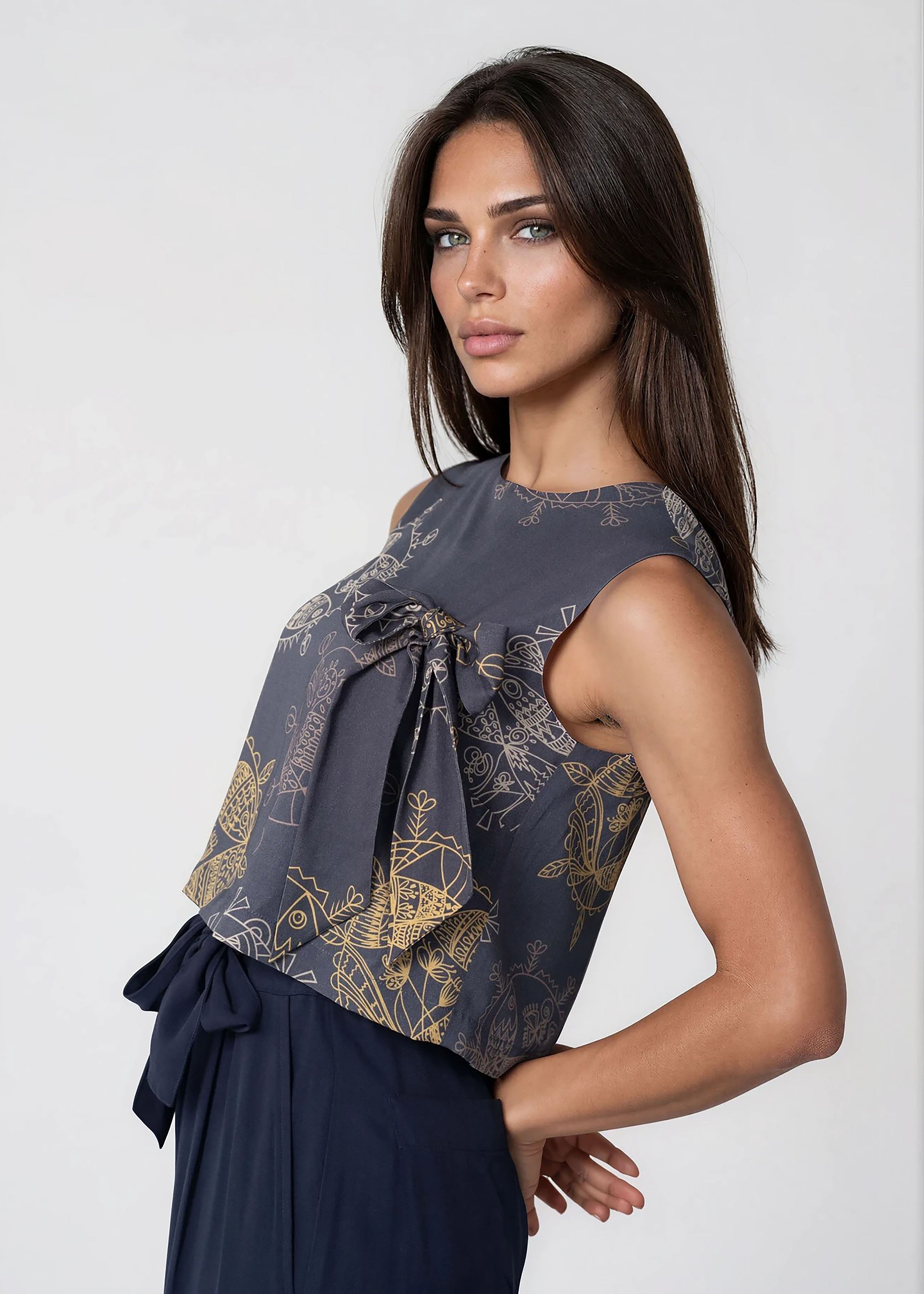 Woman wearing a midnight blue cropped sleeveless bowtie top with round neckline and relaxed fit