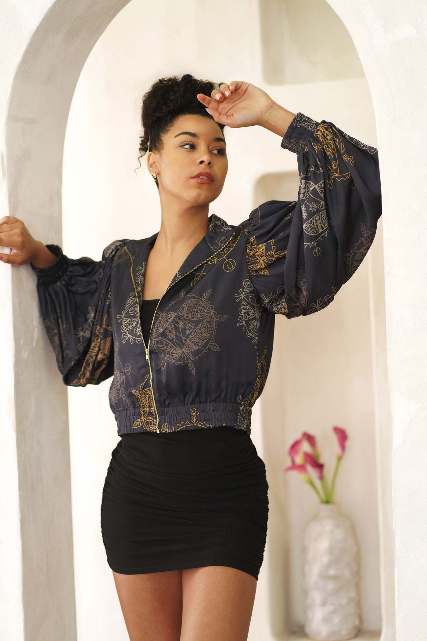 Woman wearing a stylish cropped bomber jacket with oversized bell sleeves and front zipper