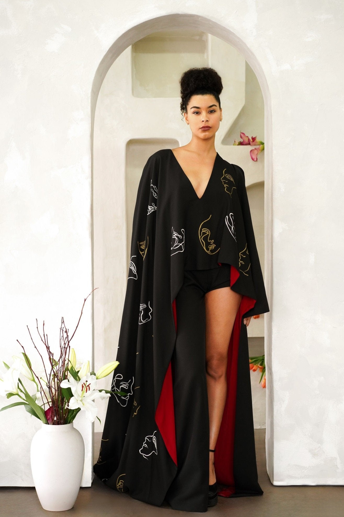 Model wearing Invisible Government asymmetrical hand-painted cape and one-leg silk wool pants with a V-neck and wide-leg design