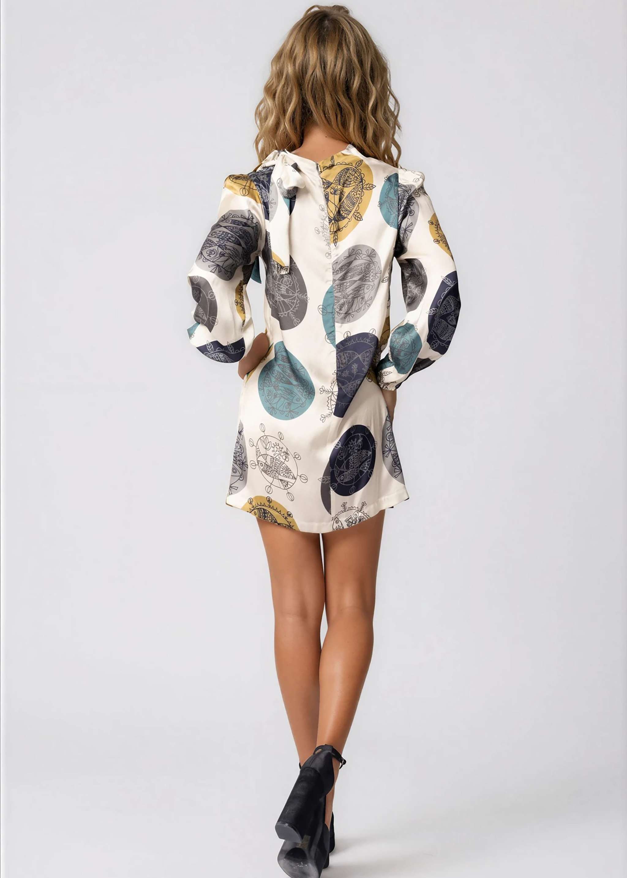 Woman wearing high neck mini dress with long bell sleeves and neck tie in lightweight fabric