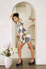 Woman wearing a high neck mini dress with long bell sleeves and tie detail in blue ocean pattern